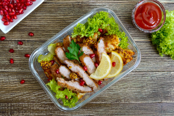 木桌上的玻璃碗里盛着烤土豆、肉、青菜和辣酱的热沙拉。午餐盒。前视图。图片下载