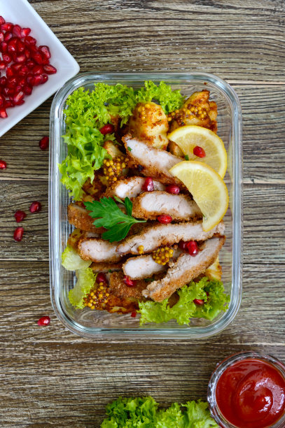 木桌上的玻璃碗里盛着烤土豆、肉、青菜和辣酱的热沙拉。午餐盒。前视图。图片下载