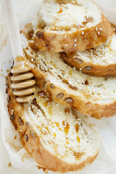 小麦吐司早餐黄油，蜂蜜和芝麻在白色背景特写俯视图。健康的早餐概念图片下载