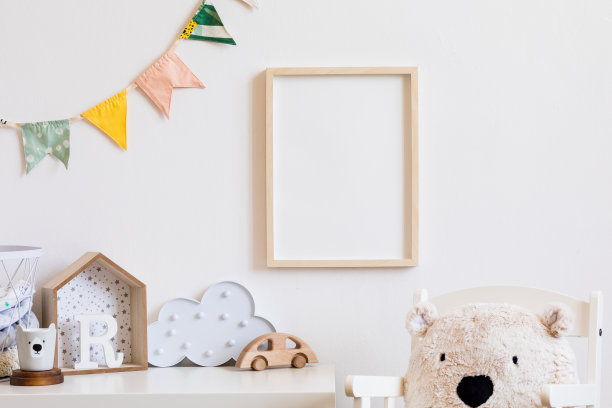 时尚的斯堪的纳维亚儿童房间模拟照片海报框架上的白色墙壁。可爱的现代室内婴儿箱，泰迪熊，玩具。木制配件和彩旗。真实的照片。图片下载