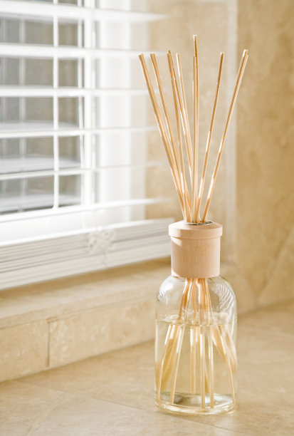 阳光透过百叶窗照射到浴室石砖柜台上的香味扩散器上。洁净、明亮、清新的家居家居装饰元素细节。图片下载