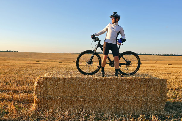 骑自行车的人把自行车放在收割过的麦田里图片下载