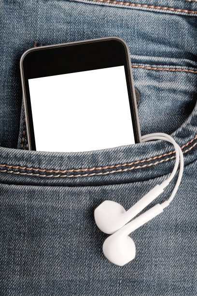 牛仔裤口袋里装着现代智能手机和耳机。图片下载