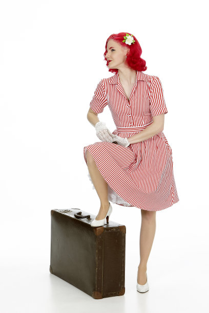 年轻女子穿着复古红裙，红头发，带着旅行箱图片下载