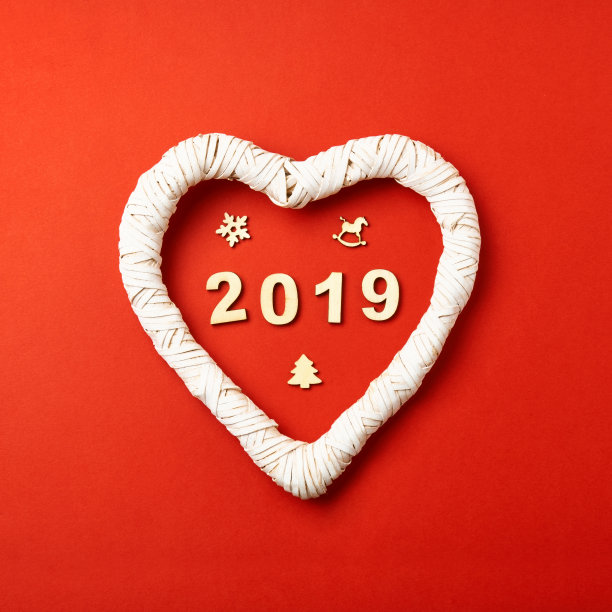 圣诞贺卡。红色背景上刻有2019年字样的白色柳条心形图案在中间，木制的圣诞人物形式为雪花、圣诞树、星星、马、鹿图片下载