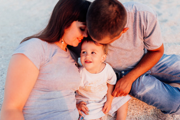 年轻的一家人坐在海边图片下载
