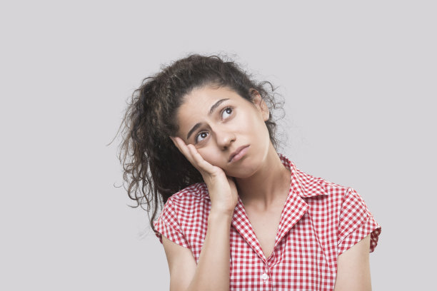 悲伤的年轻女子的肖像梦想与沉思的面部表情在灰色的背景图片下载