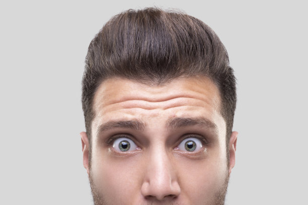 特写的年轻男子与震惊的面部表情在灰色的背景图片下载