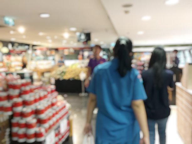 模糊的形象收银员与长队的人在超市的收银台。顾客用信用卡或现金支付给店员，装满一车的杂货。出纳登记的概念图片下载