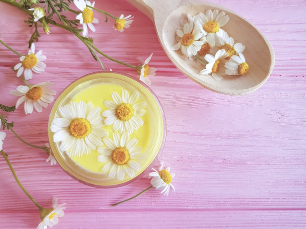 化妆霜，粉红色木质背景上的洋甘菊花图片下载