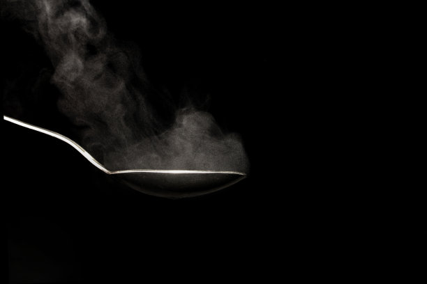 滚烫的钢勺在黑色背景与蒸汽从水图片下载