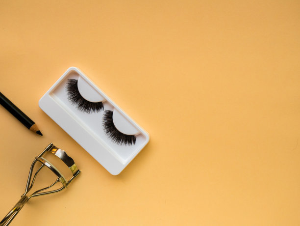 假睫毛，卷睫毛器和黄色背景的眼线图片下载