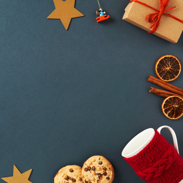 圣诞frame-postcard。圣诞装饰图案的圣诞玩具，一个装有礼物的盒子，姜饼，一个在红色风景的杯子，星星，肉桂棒，干橙杯在一个黑暗的背景图片下载