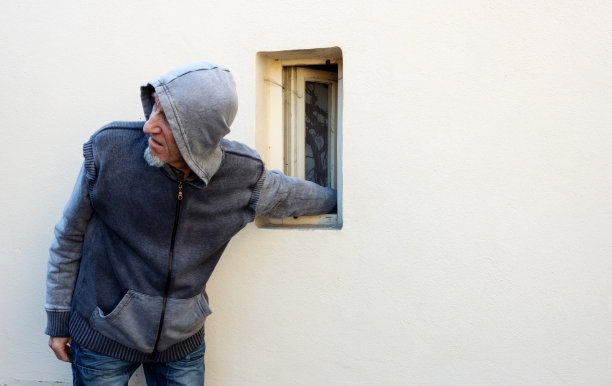 夜贼、小偷或强盗正用胳膊从小窗户里偷东西图片下载