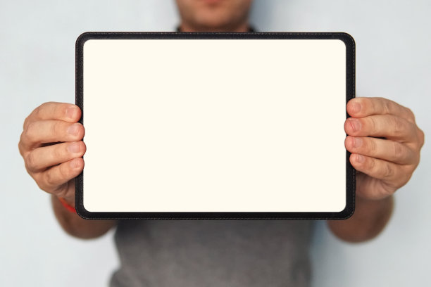 男人手中的数字平板电脑的特写。上半张照片，一个男人拿着一个平板电脑，手里拿着一个白色的屏幕。人在孤立的背景显示数字平板与空白触摸板图片下载
