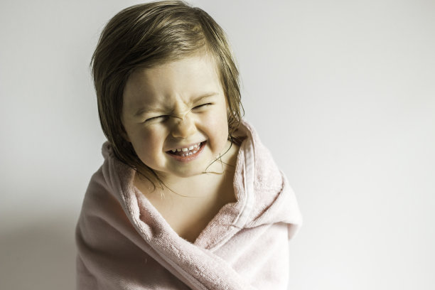 用毛巾包裹的有趣的情绪蹒跚学步的女婴图片下载