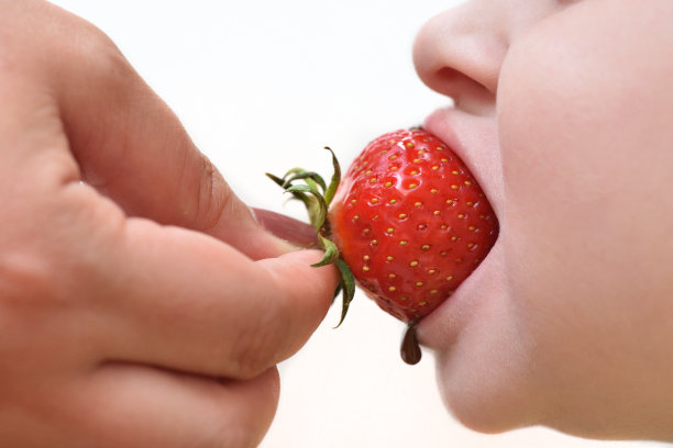妈妈用草莓和融化的巧克力喂孩子。特写镜头图片下载