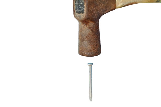 白色背景中的旧锤子砸在钉子上图片下载