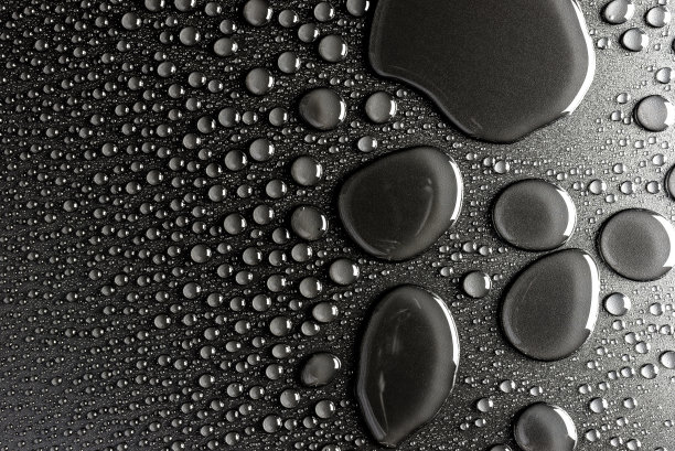 水滴在一个黑色的，哑光背景照亮了一个微妙的光。图片下载