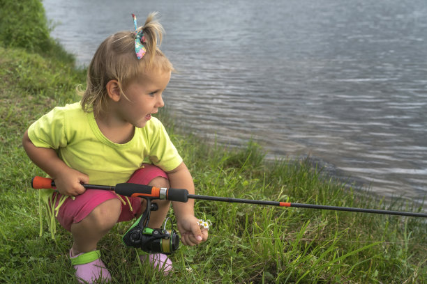 一个带钓具的小女孩在湖边钓鱼图片下载