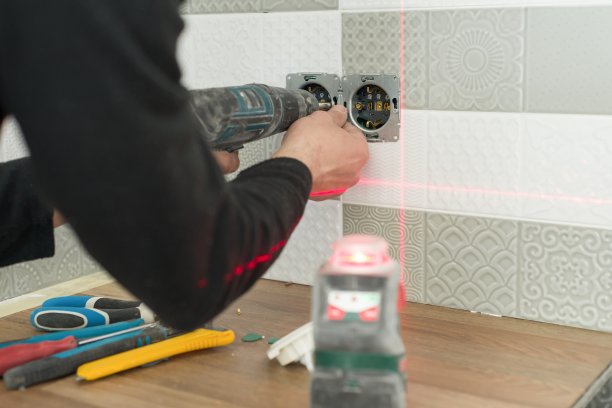 电工使用红外激光水平仪安装电源插座。厨房装修及施工图片下载