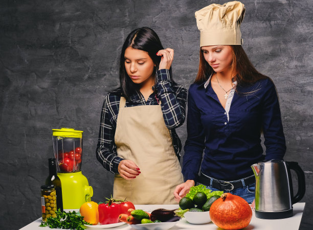 两个女人正在用搅拌机准备素食蔬菜汁。图片下载