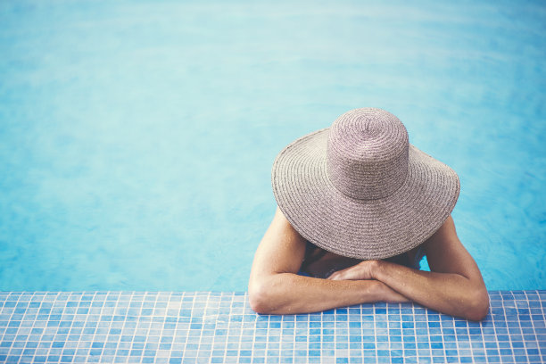 晒黑的女人双臂交叉在游泳池里放松图片下载