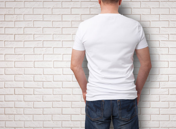男子穿着空白t恤在灰色砖墙背景与复制空间。t恤设计和人的概念-近距离的人在空白的白色t恤。用于模拟模板设计。后视图图片下载