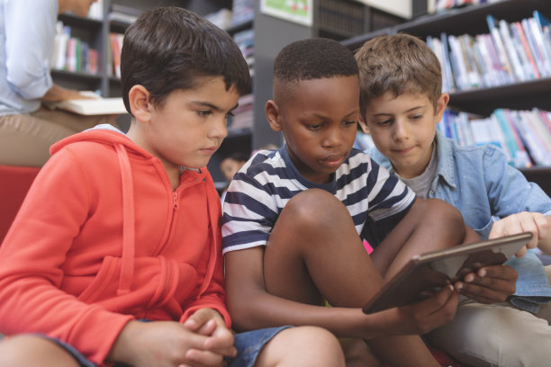 学生们坐在图书馆的坐垫上使用数字平板电脑图片下载