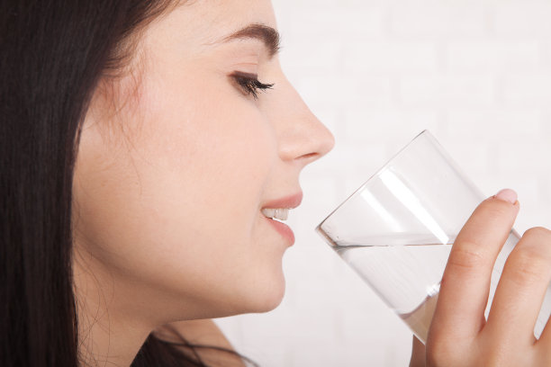 女孩在家里喝水。早餐前喝一杯水。图片下载