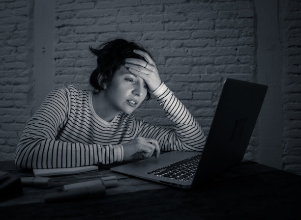 黑白照片:一位劳累过度的女学生晚上在笔记本电脑上工作，试图不睡着。感觉疲劳，想集中精神。在学习或工作的概念中。图片下载