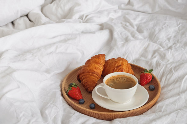 白色床单上的咖啡和羊角面包特写图片下载