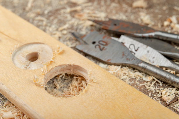 用叶片钻在刨花板上钻孔。木工车间的木工工作光背景。图片下载