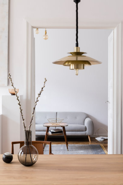 时尚和现代的室内设计与木桌子，椅子，沙发和挂金灯。简约的空间，设计家具和配件。白色的墙壁。真实的照片。图片下载