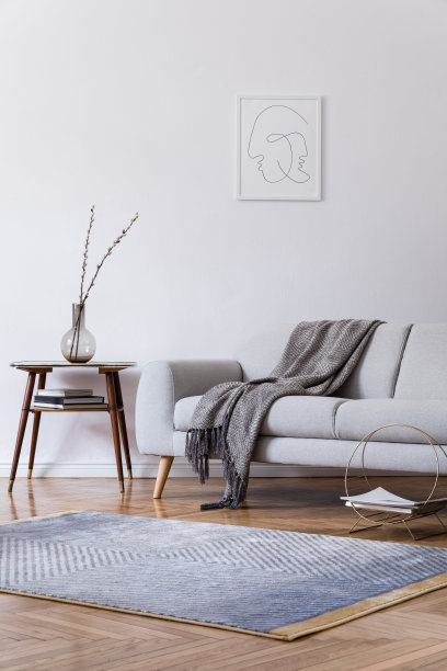时尚的室内设计，设计灰色沙发和复古小桌子的家庭空间。客厅与设计配件和模拟海报框架。优雅的装饰。棕色镶木地板配现代地毯。图片下载