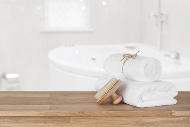 白色的浴巾放在木质的桌子上，在浴室背景上图片下载