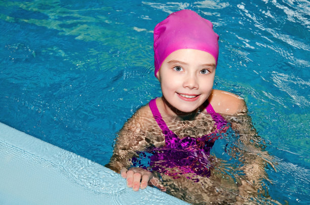 可爱的微笑小女孩的肖像，孩子游泳在粉红色的泳衣和帽子在游泳池图片下载
