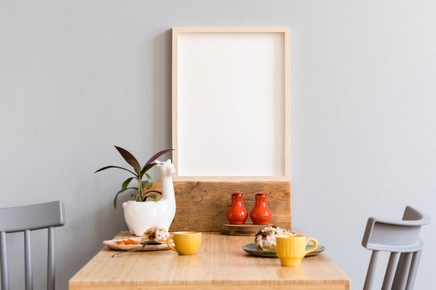 时尚舒适的厨房空间，木制的桌子与模拟的相框，美丽的植物，设计家具和美味的甜点。斯堪的纳维亚室内装饰与厨房配件。图片下载