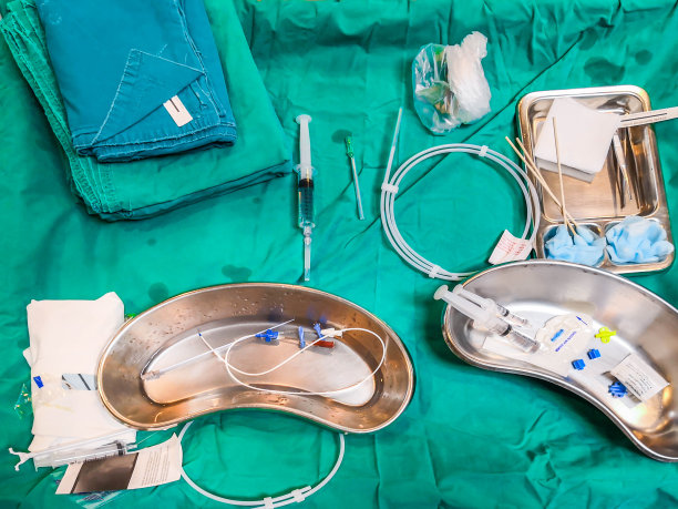 组置敷料外周置入中心置管用无菌手术工具，夹钳、注射器、扩张器放在医院手术托盘上的绿色布条上均为无菌置管图片下载