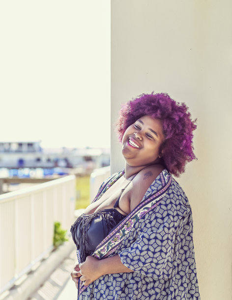 年轻的非洲裔美国妇女与紫色头发高兴，微笑和自信图片下载