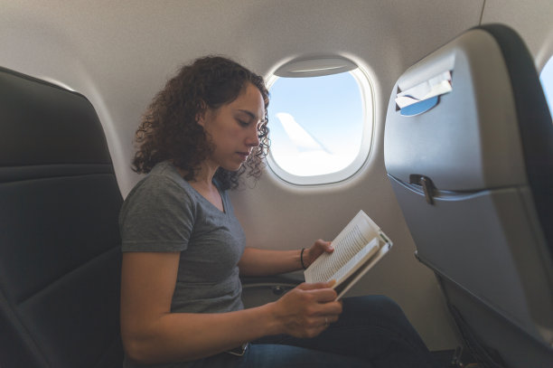 女旅行者在飞机上看书图片下载