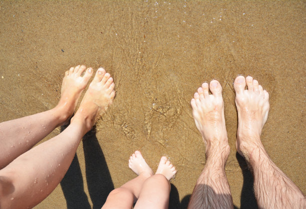家庭度假的概念。幸福的家庭腿上有海浪和沙滩的拷贝空间。图片下载