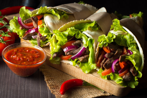 照片上的墨西哥三明治食物，玉米煎饼，菲希塔，玉米饼，玉米粉圆饼，牛肉，鸡肉，新鲜蔬菜在乡村的木制背景。快餐的概念。健康的午餐小吃。副本的空间。图片下载