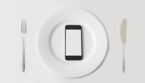 配有刀叉的白色盘子上有拷贝空间的智能手机。图片下载