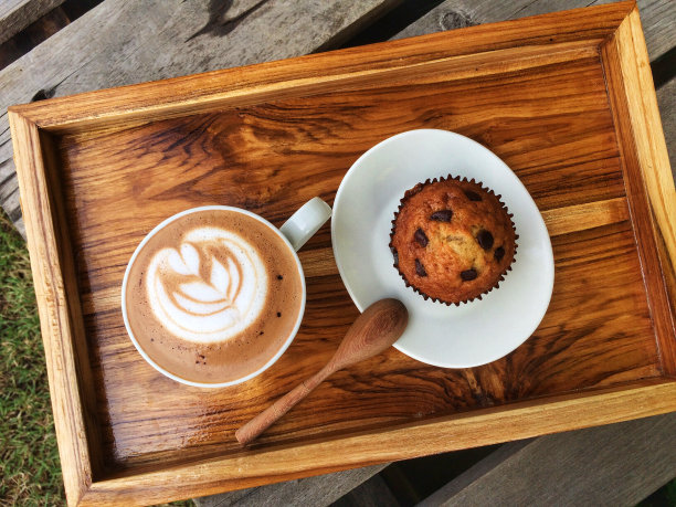 俯视图，拿铁咖啡，木勺和香蕉巧克力杯蛋糕在木托盘上，美味的早餐图片下载