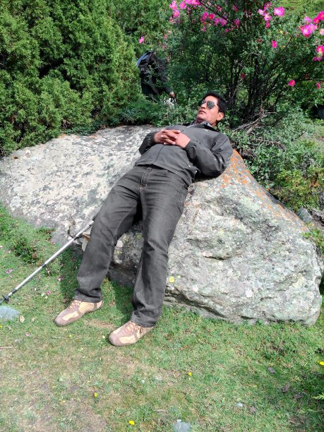 一个徒步旅行者在他背后的一块大石头上放松图片下载