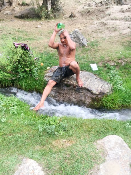 在山间徒步旅行时在淡水溪中洗澡的游客图片下载