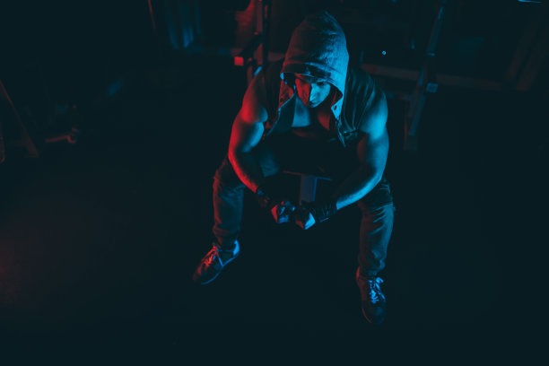 强壮的男子集中精力在黑暗的健身房举重图片下载