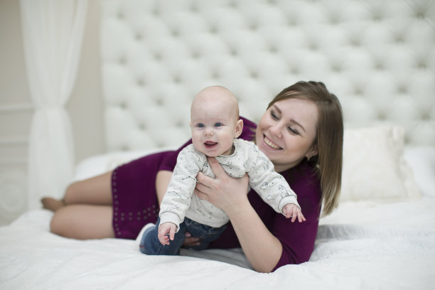 妈妈和她的小儿子在床上。母亲和婴儿图片下载