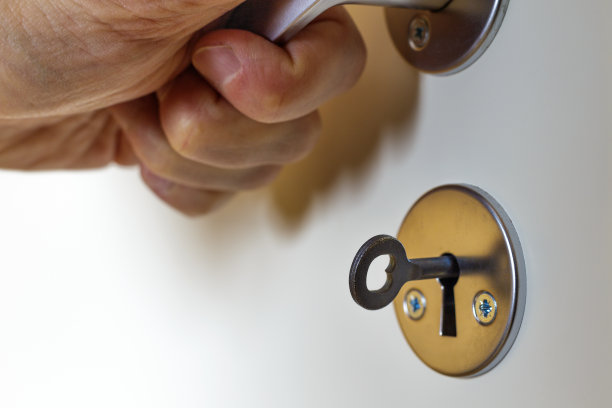 特写的高级男子的手推动金属门把手，钥匙在锁眼上的白色门图片下载